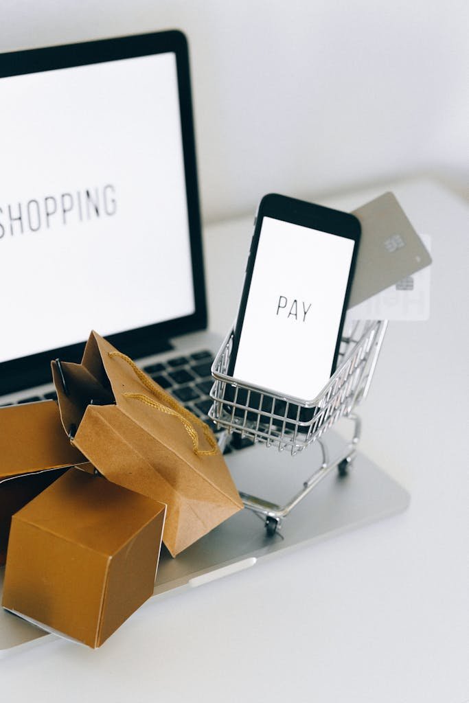 A Miniature Shopping Cart and Smartphone on MacBook Laptop